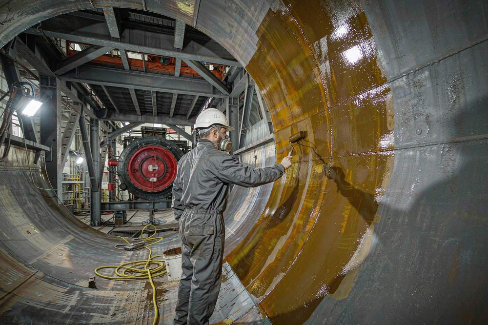 technician rolling amber epoxy coating onto the inside wall of a steel tank